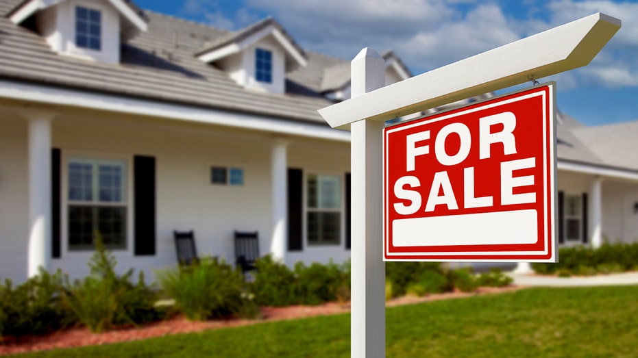 A red and white "for sale" sign in front of a house